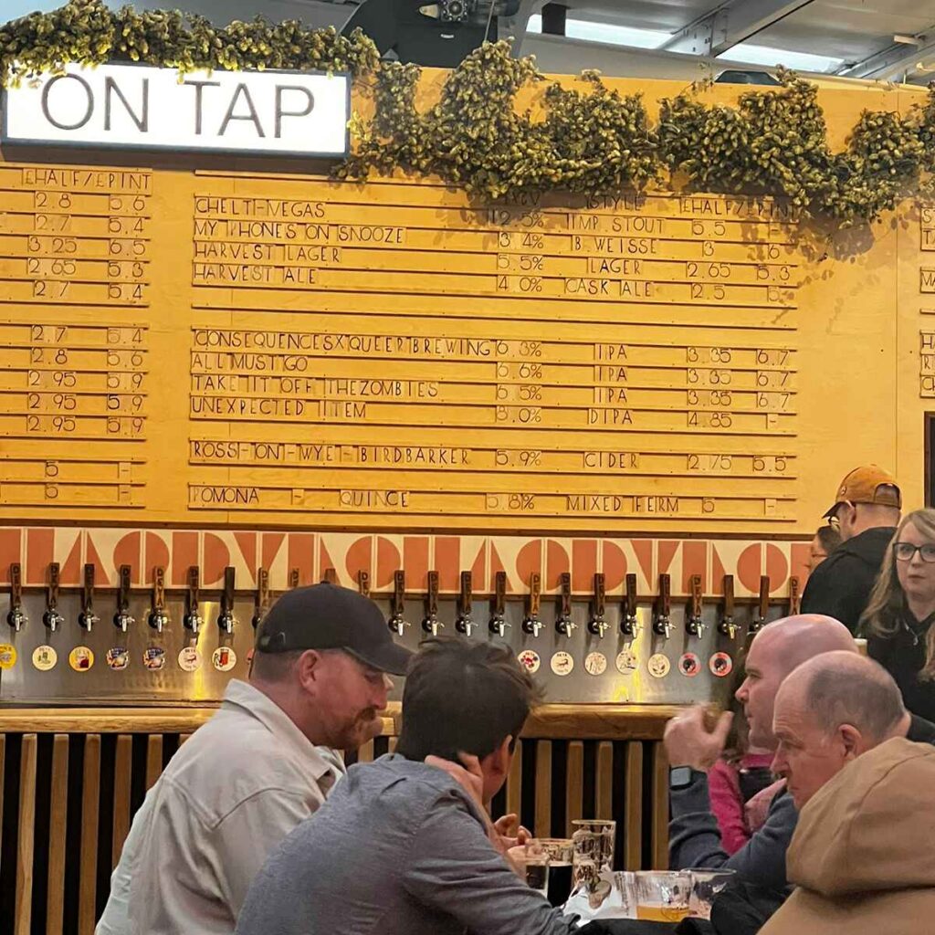 A long row of craft beer ale on a wall with a menu of the alcohol on offer and the words 'on tap' above.