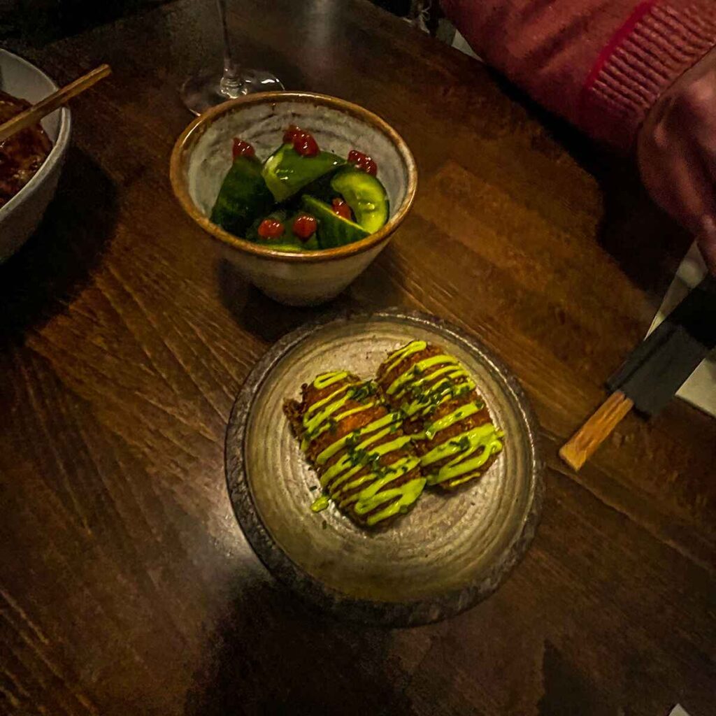 A plate of fried food with green dressing with Japanese pickles