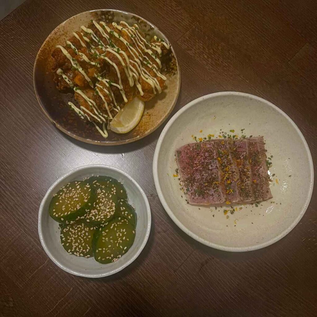 Three bowls of Japanese inspired food covered in mayo, chilis and sesame seeds