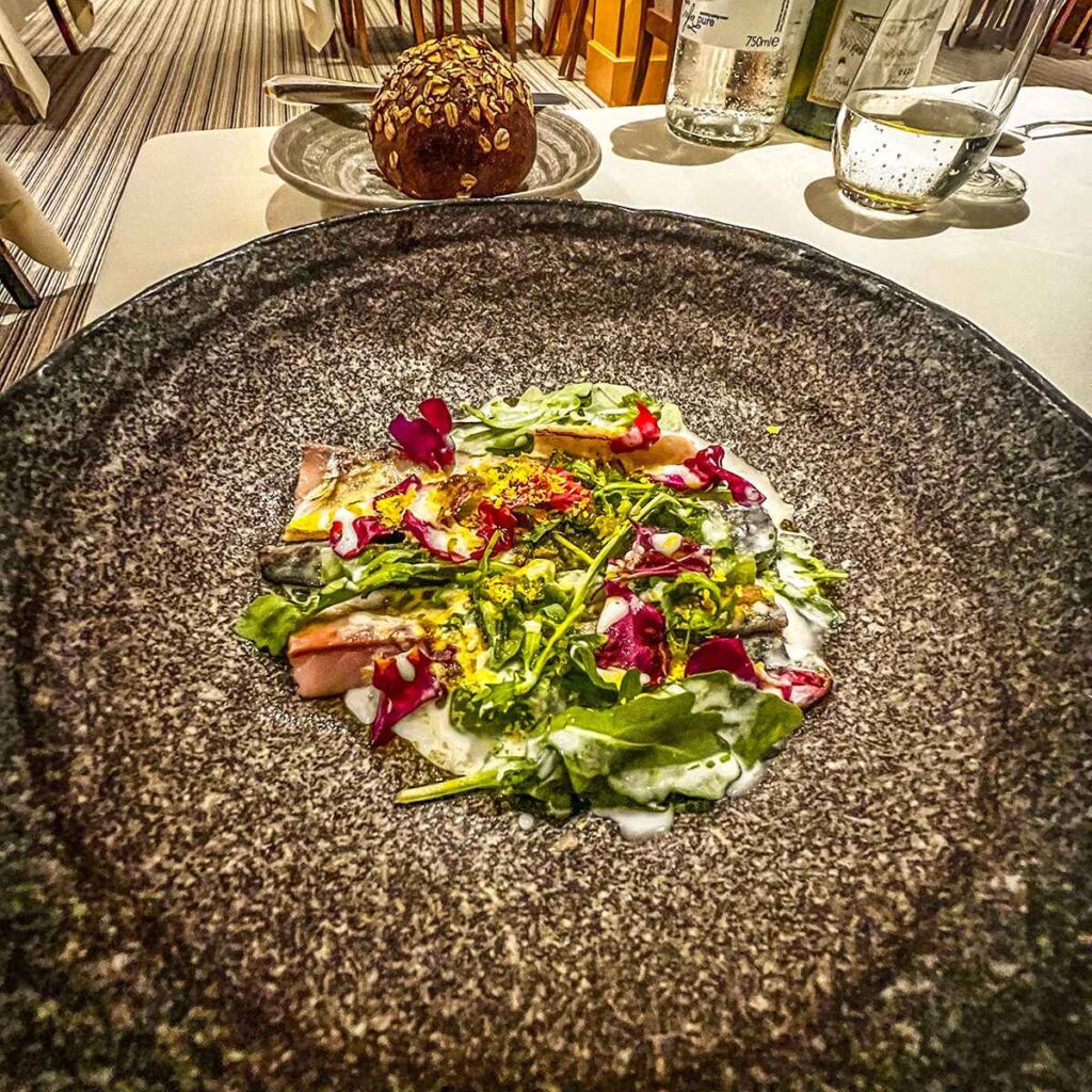 A dish with bread roll in the background at A huge cheese board of many different cheese varieties at Le Champignon Sauvage, Cheltenham