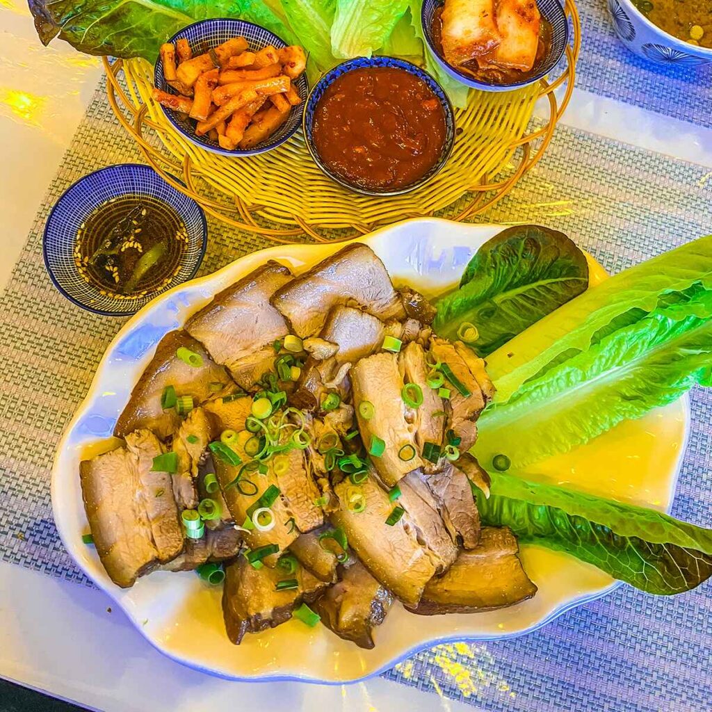 A plate of pork and small bowls of Korean food