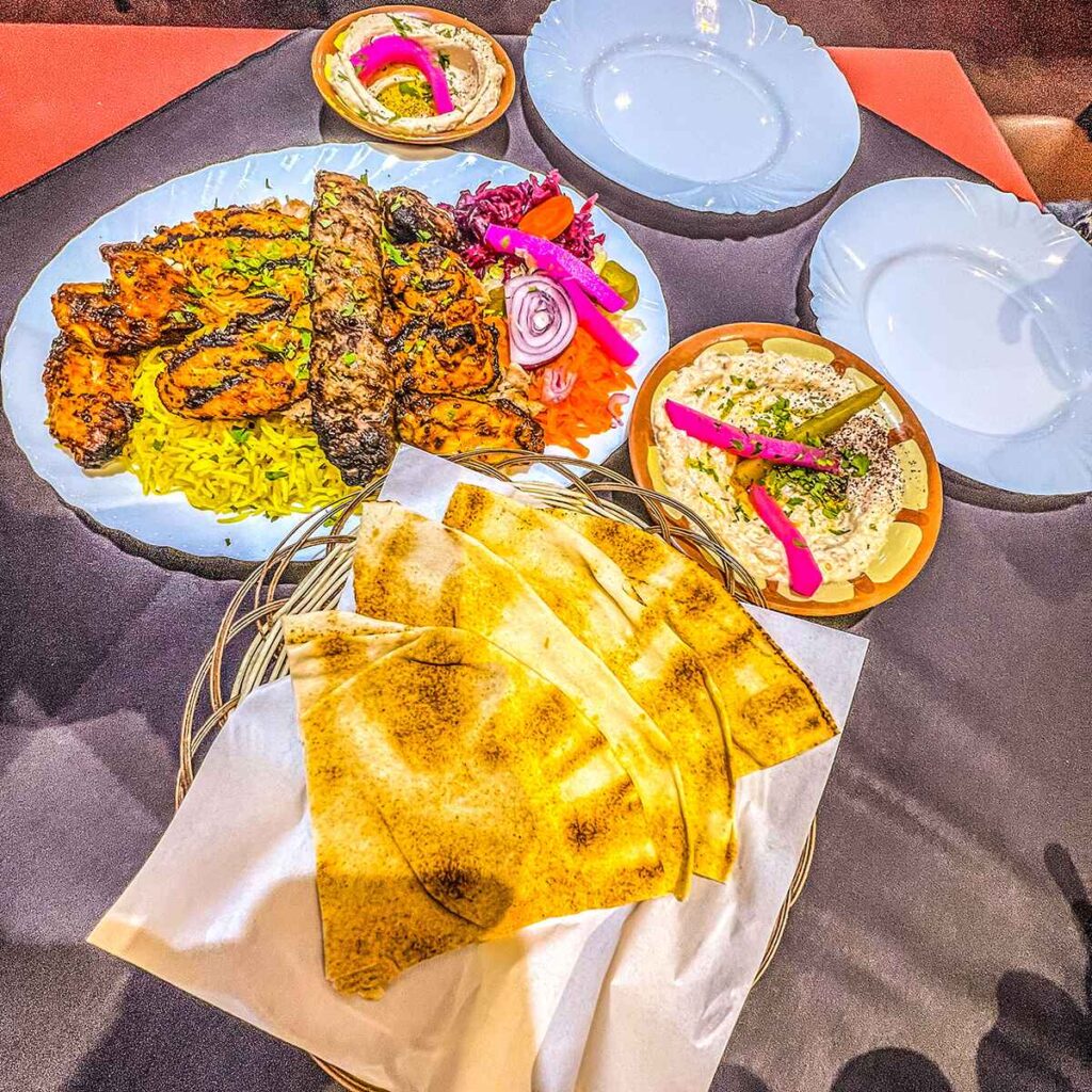 An Arabic mixed grill on rice with flat breads and dips