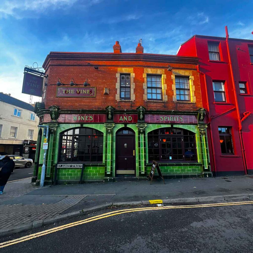 Glazed tiled green exterior of The Vine pub in Cheltenham