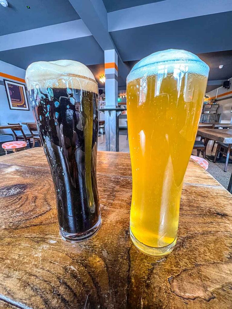 Two pints of beer resting on a table. One dark stout and one light coloured