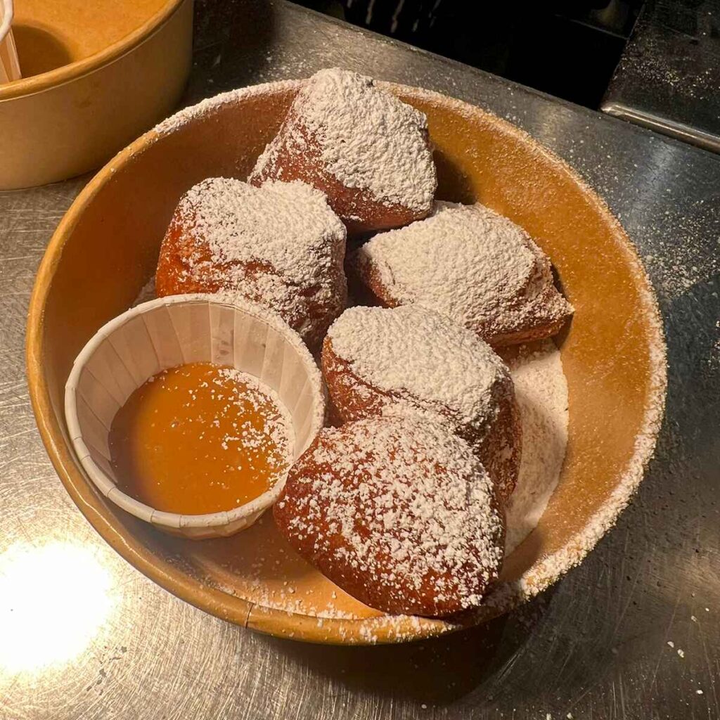 light pillowy beignets with icing sugar and fudge sauce