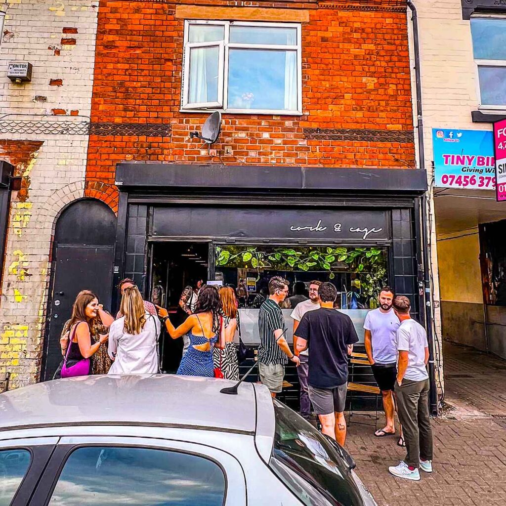 Front of Cork and cage bar in Birmingham with a group of people stood outside