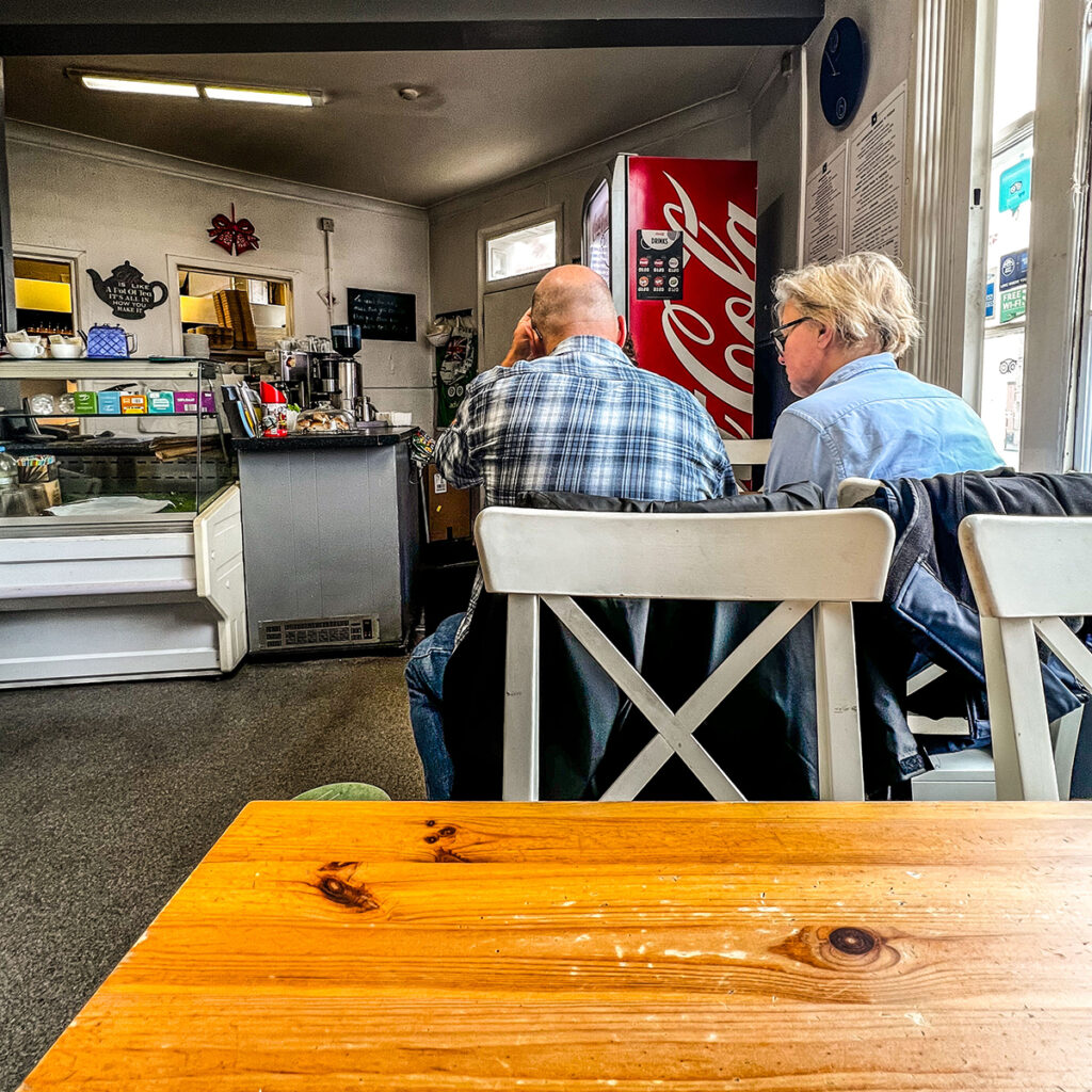 Inside the Hylton Cafe. Two people sat next to each other eating.

