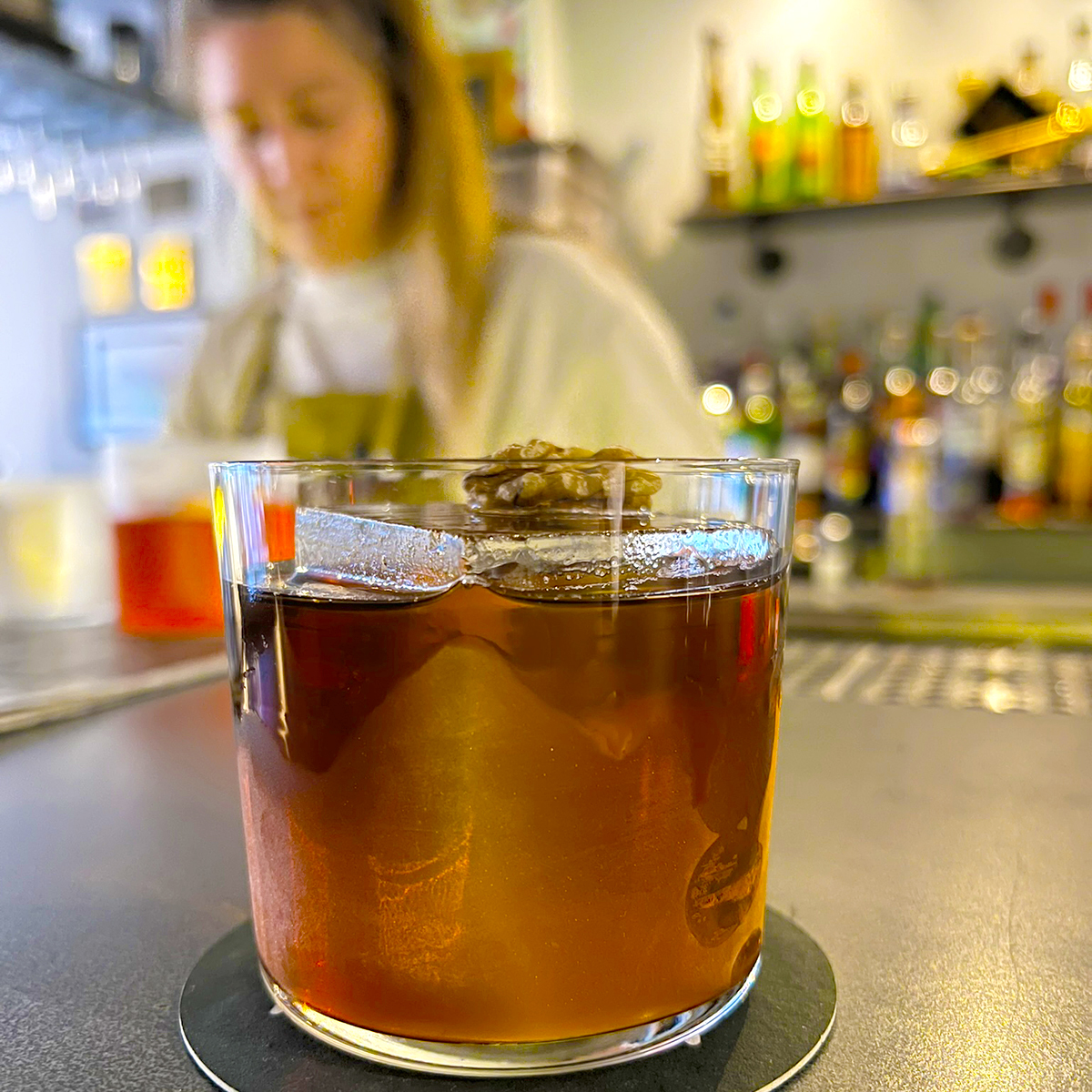 One of the best cocktail bars in Birmingham with a dark cocktail with ice on a bar countertop.